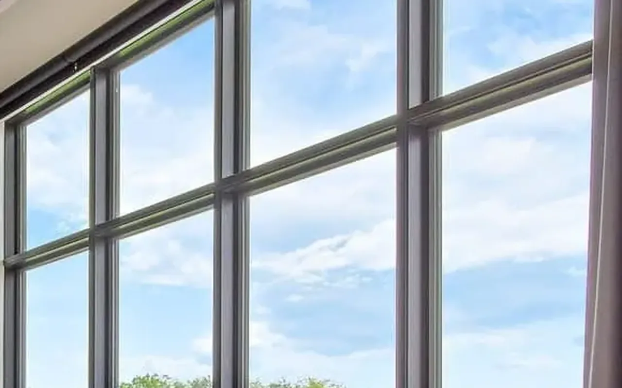 Floor-to-ceiling black-framed windows in a living room looking out on trees